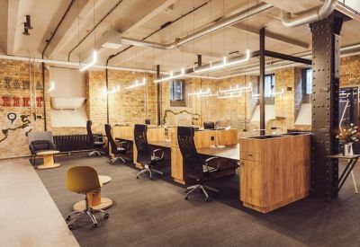 Modern open-plan office with wooden desks and industrial brick walls.