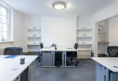 Minimalist office suite with white desks, recessed shelving, and a large sash window.