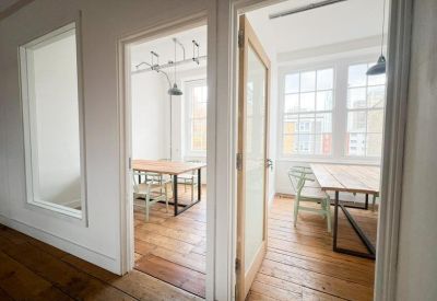Bright meeting room with a wooden table seen through an open glass door.