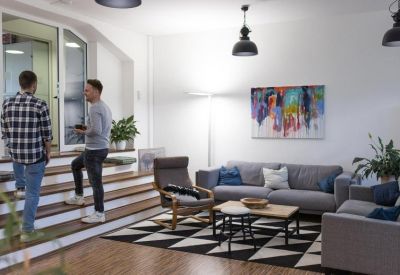 Modern lounge area with a grey sofa, geometric rug, and wall art.