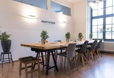 Meeting room with a long wooden table, grey chairs, and potted plants.