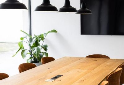 Long wooden board table under modern black pendant lights.