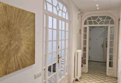 Elegant hallway with tiled floors, arched glass doors, and gold sunburst wall art.
