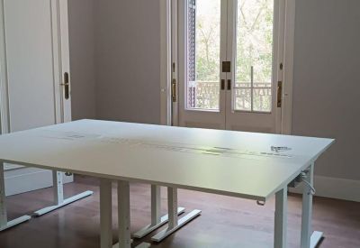 Bright private office with white adjustable desks and tall French doors.