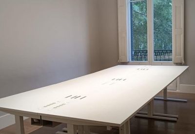 Wide white conference table in a minimalist room with natural light.
