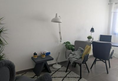 Bright workspace featuring a modern grey chair, floor lamp, and indoor plants.