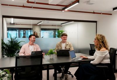 Team members collaborating at a dark conference table in a modern meeting room.