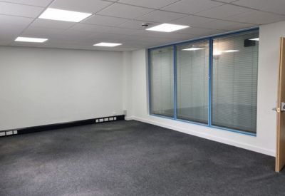 Spacious empty office suite with grey carpeting and recessed ceiling lights.