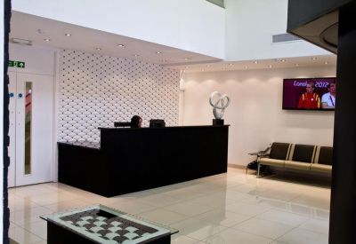 Modern white reception area with a sleek black desk and seating area.