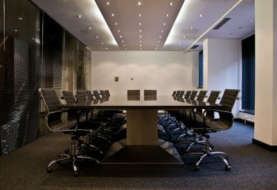 Spacious boardroom with a large central table and black mesh chairs.