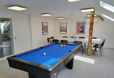 Spacious communal breakout room with a blue billiards table and dining seating.