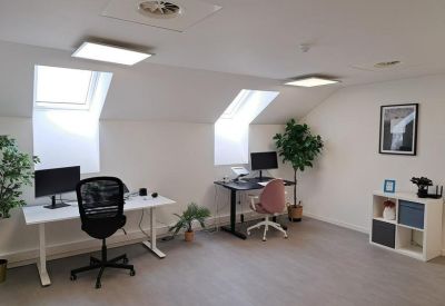 Bright attic-style coworking space with white desks and natural light from skylights.