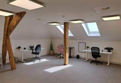 Open office area featuring modern height-adjustable desks and rustic wooden pillars.