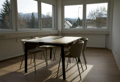 Bright meeting area with a wooden table, neutral chairs, and large windows overlooking the city.