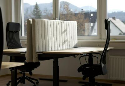 Individual sit-stand desk setup with privacy partitioning and an ergonomic chair.