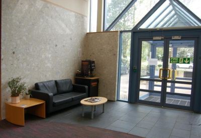 Reception lobby area with a black leather sofa and glass door entrance.