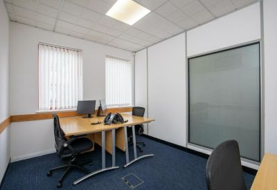 Private office suite with two desks and vertical window blinds.