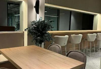 Modern communal breakout area with high-top bar seating and wooden dining table.