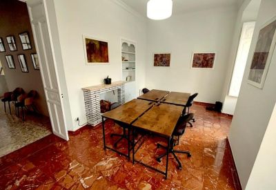 Spacious workspace with wood-top desks, ornate tiled flooring, and a decorative fireplace.