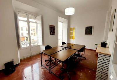 Workspace with ample natural light from a French balcony and modern wooden desks.