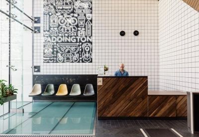 Reception desk with dark wood paneling, a tiled wall, and a colorful Paddington sign.