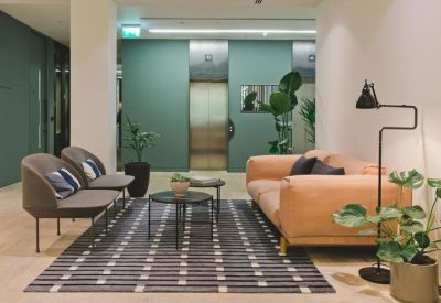 Comfortable lounge area with an orange sofa and green walls near the elevators.