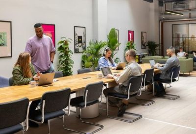 Large open-plan coworking space with a long wooden desk and vibrant wall art.