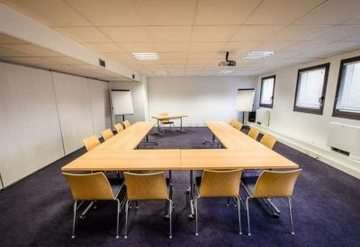 Hollow square meeting table setup in a bright room with purple flooring and white board.