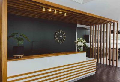 Modern reception desk with dark feature wall and vertical wood slat screening.