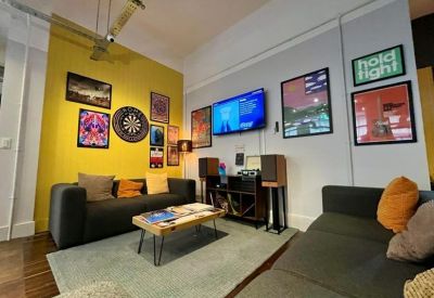 Vibrant lounge area with a yellow feature wall, record player, and comfortable sofas.