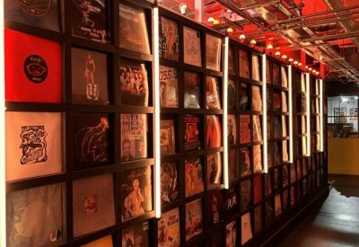Themed display wall featuring rows of vinyl record covers illuminated by neon lights.