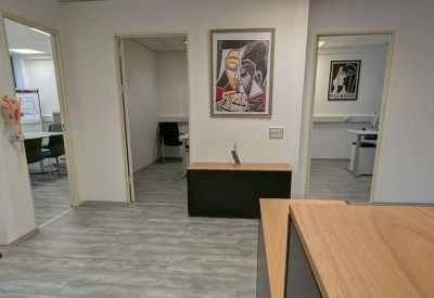 Spacious reception or hallway area with grey wood-style flooring and colorful wall art.