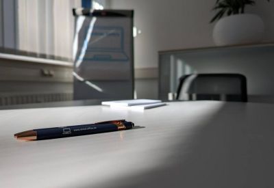 Close-up of a desk with a pen and notepad in a bright, sunlit office.