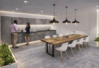 Communal kitchen area with a long dining table and hanging lights.