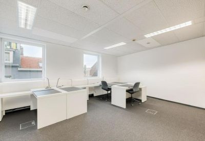 Spacious office suite with white desks and windows overlooking city rooftops.