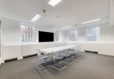 Professional meeting room with a long white table and transparent modern chairs.