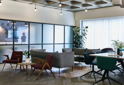 Spacious breakout lounge with colorful mid-century modern chairs and large frosted windows.