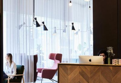 Reception area with a wooden herringbone desk and soft lounge seating behind a sheer curtain.