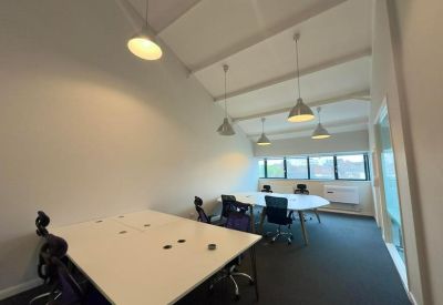 Meeting room with a large white table, blue office chairs, and modern pendant lighting.