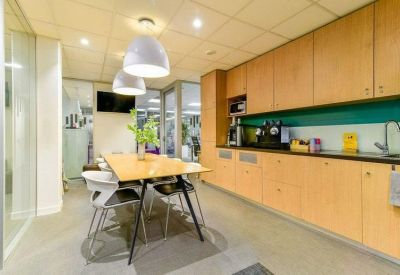 Modern communal kitchen and breakout area with light wood cabinetry.