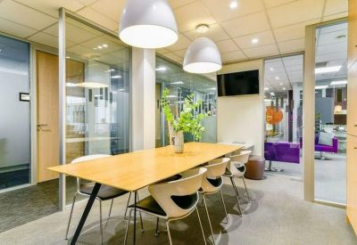 Meeting room with wooden table and distinctive white pendant lights.
