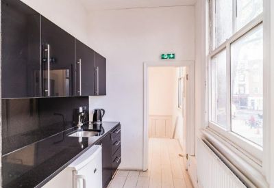 Modern galley kitchen with sleek black cabinetry and white flooring.