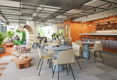 Spacious coworking lounge with diverse seating, round tables, and an orange accent wall.