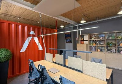 Bright coworking area featuring a bold red shipping container wall and light wood furniture.