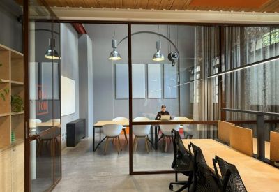 Glass-walled conference room with white chairs and modern pendant lighting.