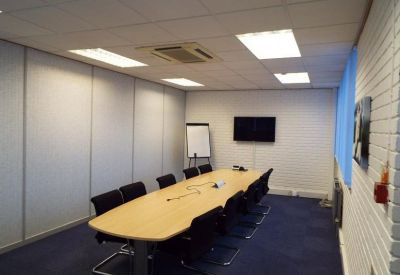 Meeting room with large oval table, black chairs, and a whiteboard.