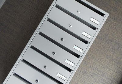 Bank of grey secure mailboxes mounted on a wall.