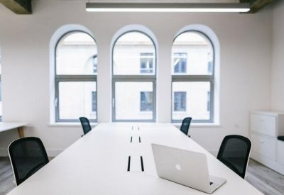 A white meeting table facing three arched windows providing ample natural light.