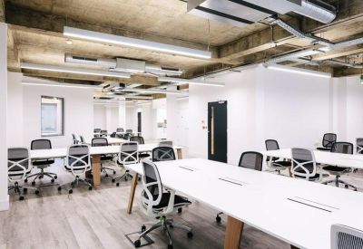 Long rows of white workstations in a bright office with exposed ductwork.