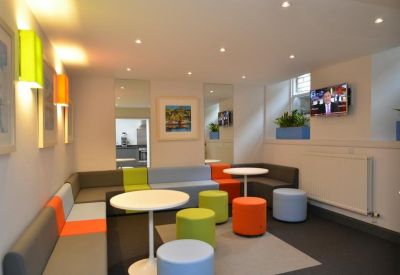 Vibrant communal breakout area with colorful modular seating and round white tables.